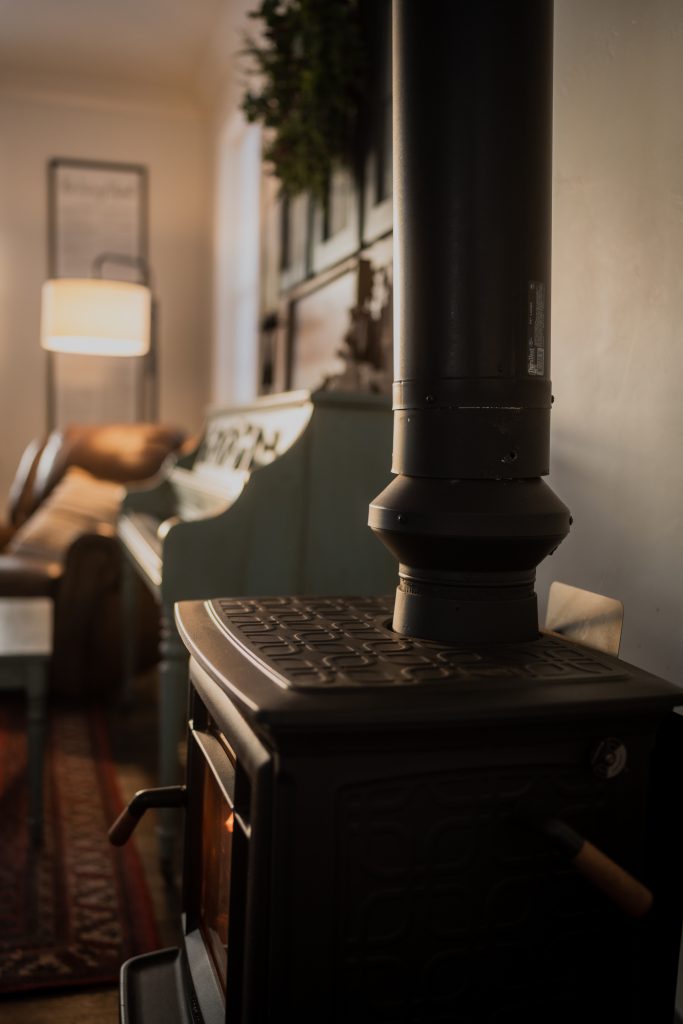 image of the atmosfire draw collar installed on a wood burning stove in the foreground with a green piano in the background